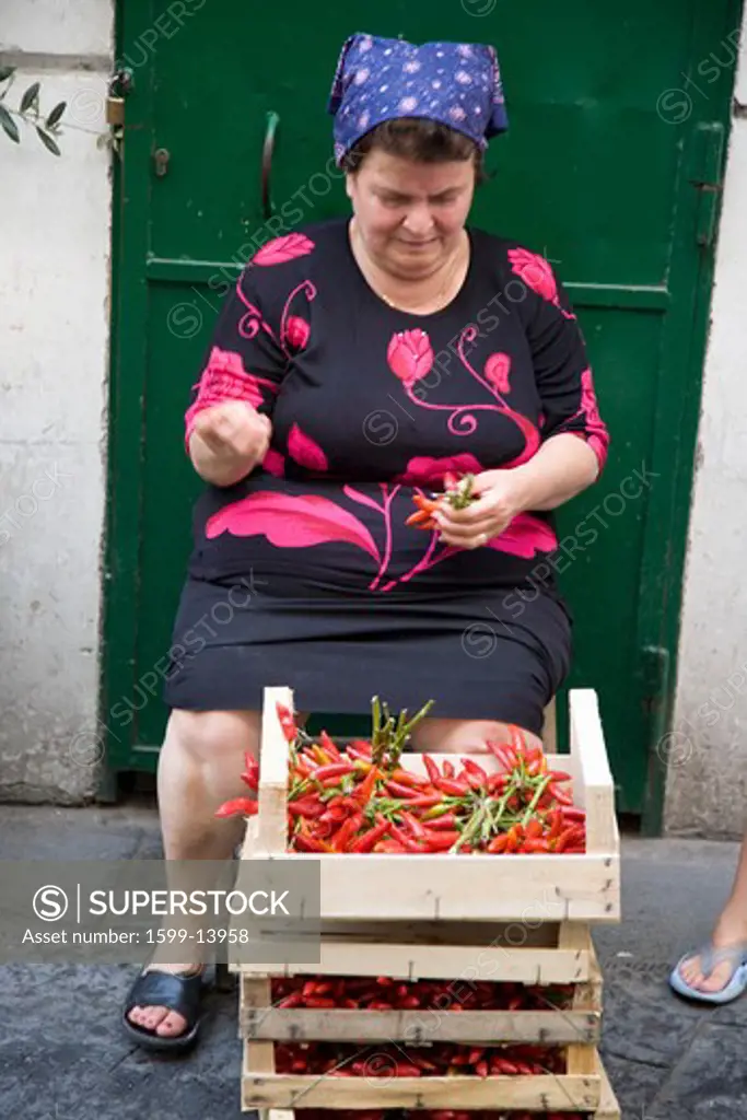 A woman sorting vegetables in front of green door in Amalfi, a town in the province of Salerno, in the region of Campania, Italy, on the Gulf of Salerno, 24 miles southeast of Naples