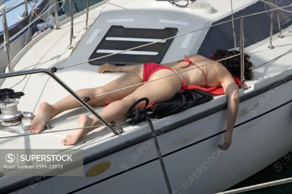 Woman sunbathing in red swimming suit on boat deck in Portoferraio, Province of Livorno, on the island of Elba in the Tuscan Archipelago of Italy, Europe
