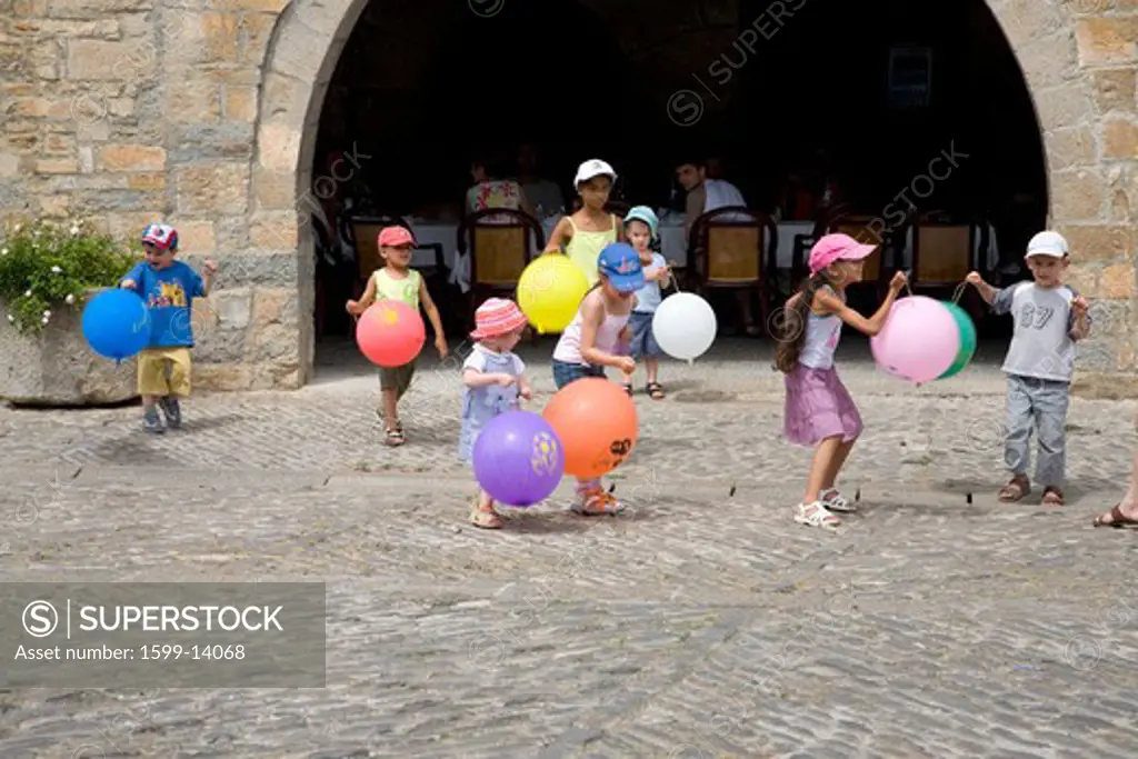 Children playing with balloons on Plaza Mayor, in Ainsa, Huesca, Spain in Pyrenees Mountains, an old walled town with hilltop views of Cinca and Ara Rivers