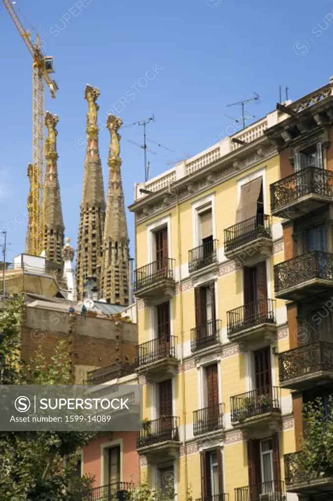 Apartments in foreground with view of Sagrada Familia Holy Family Church by architect Antoni Gaudi, Barcelona, Spain begun in 1882 and continuing to be built into the 21st Century