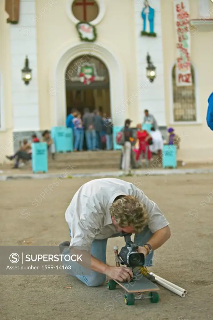San Lazaro Catholic Church and cameraman on skateboard in El Rincon, Cuba