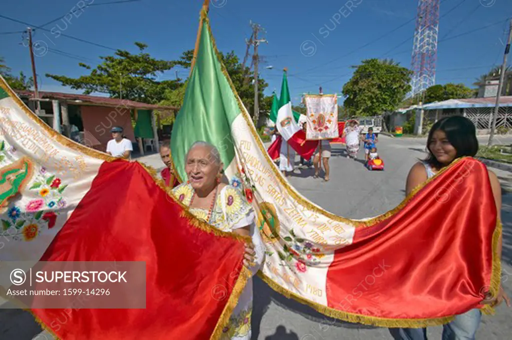 Older women and children marching through streets of Puerto Morelos carrying Mexican flag and Catholic statues, Yucatan Peninsula, Mexico, south of Cancun