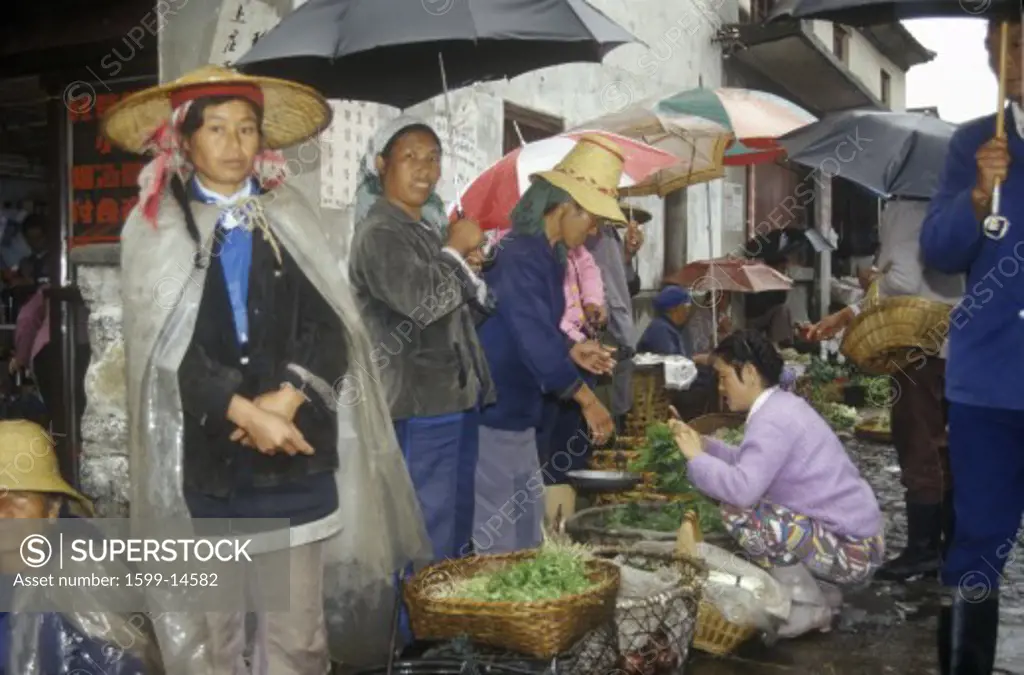 Buying vegetables in the rain at Bei People's Marketplace in Dali, Yunnan Province, People's Republic of China