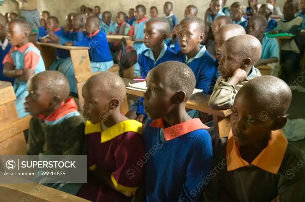 Children in blue uniforms at school behind desk near Tsavo National Park, Kenya, Africa