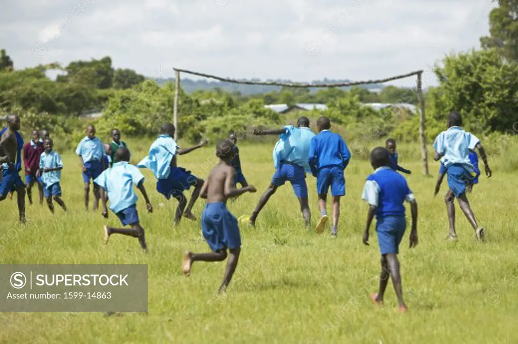 Children in blue uniforms playing soccer at school near Tsavo National Park, Kenya, Africa