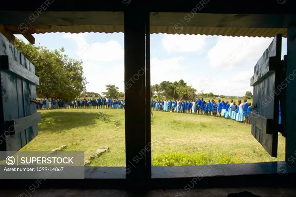 Children in blue lineup at school through interior of window in schoolroom near Tsavo National Park, Kenya, Africa