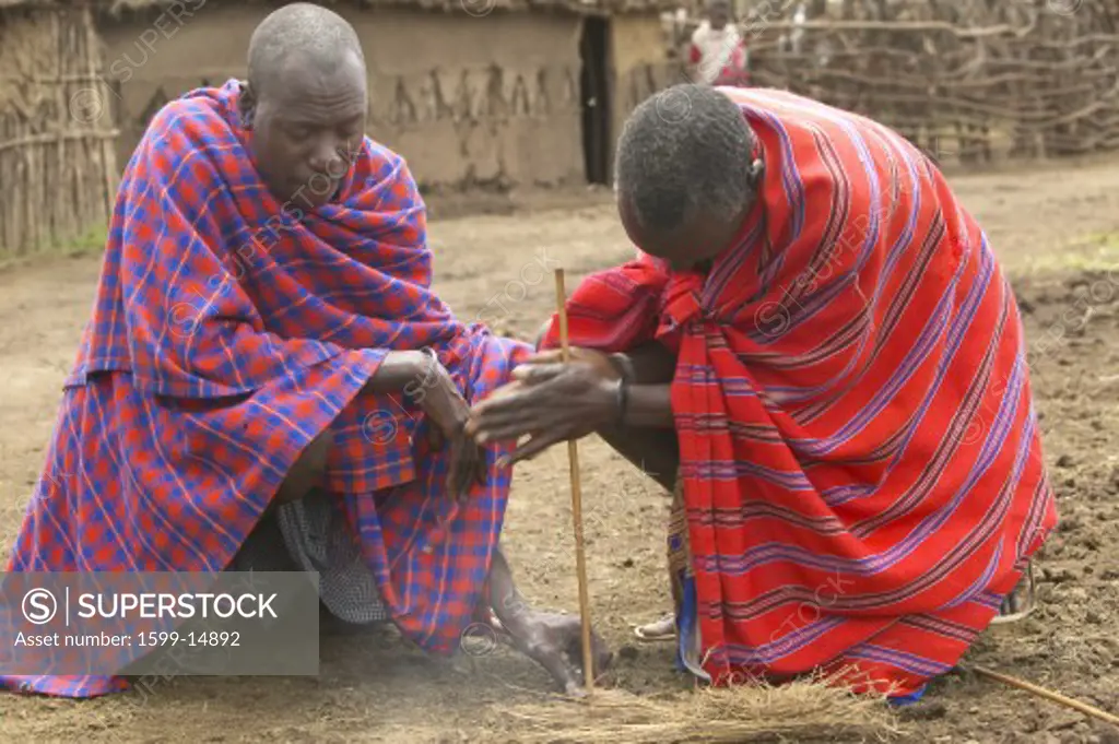 Masai male making fire by rubbing sticks together in village near Tsavo National Park, Kenya, Africa