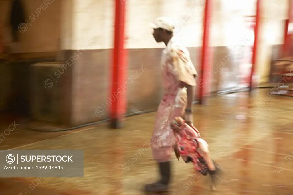 Man carrying head of animal at Nyongara slaughterhouse in Nairobi, Kenya, Africa