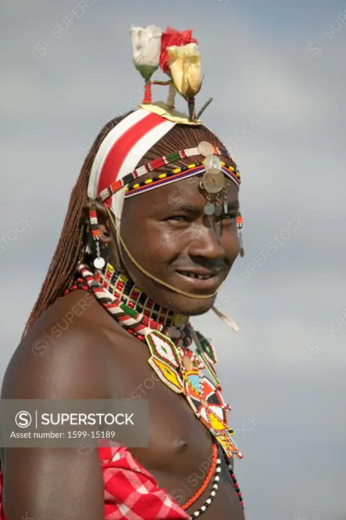 Portrait of Masai Warrior in traditional red toga and flowers on his head at Lewa Wildlife Conservancy in North Kenya, Africa