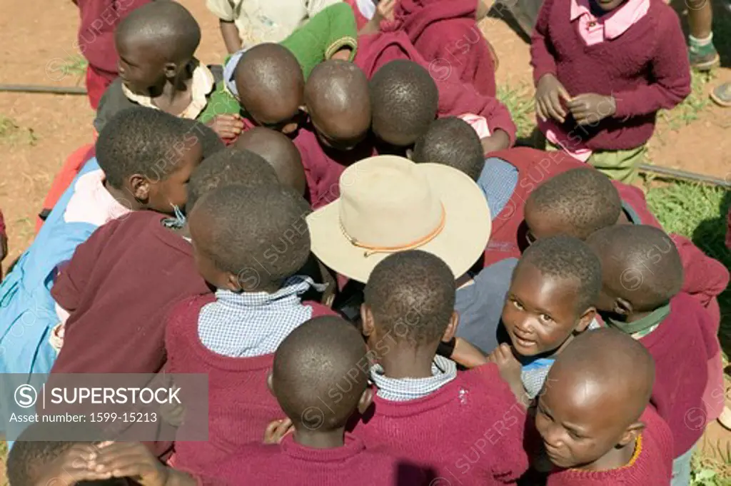 Karimba School with school children surrounding white man with straw hat on, in North Kenya, Africa
