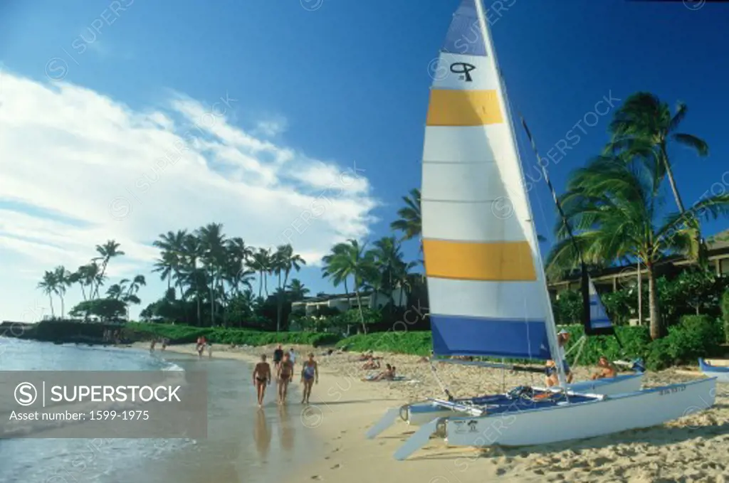 Tourists walking on the beach at a resort hotel on Hanapepe Bay in Kauai, Hawaii