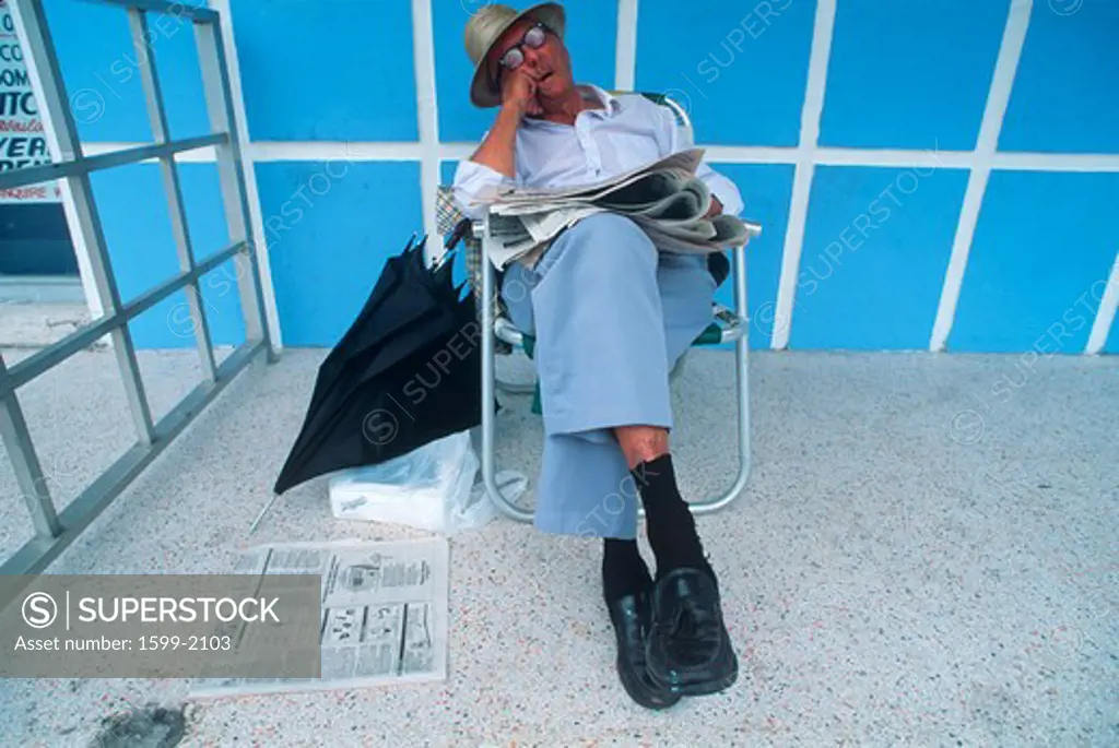 Retired man with newspaper sleeping in a lawn chair, Miami Beach, Florida