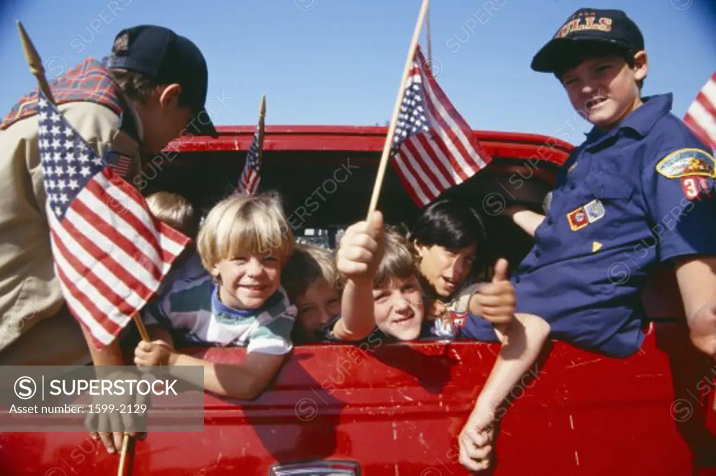 Cub Scouts waving American flags from back of car, Los Angeles, California