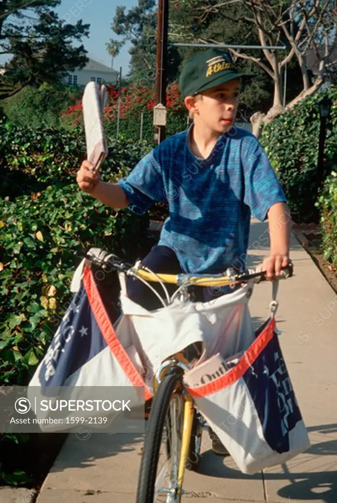 Newspaper delivery boy on bicycle, Los Angeles, California