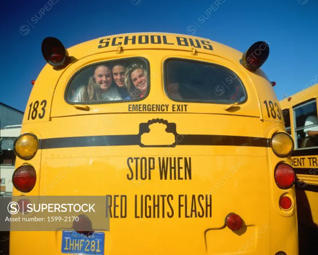 School girls smiling from back of yellow school bus