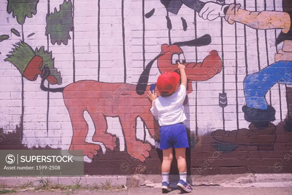 A little boy pointing to a graffiti character on a wall in Chicago, Illinois
