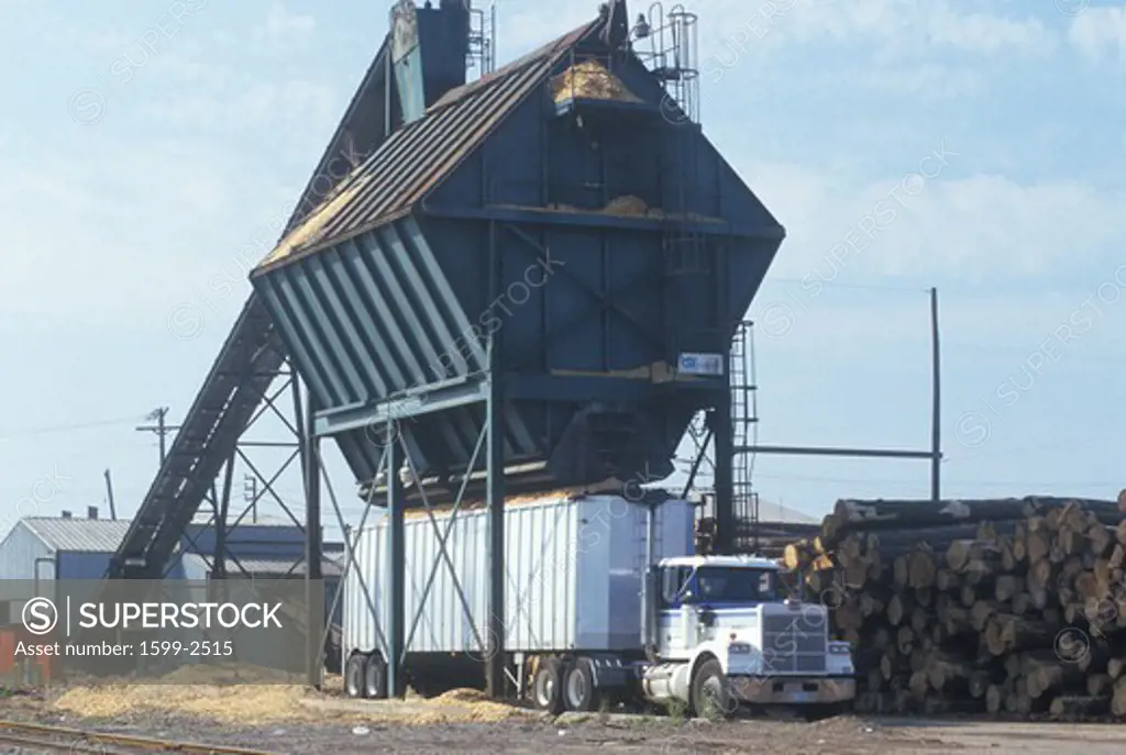 Sawdust and wood chips are loaded into a large truck at a paper mill 