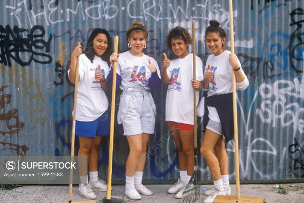 Four teenage girls participating in community cleanup on Clean and Green Day in East Los Angeles, California 
