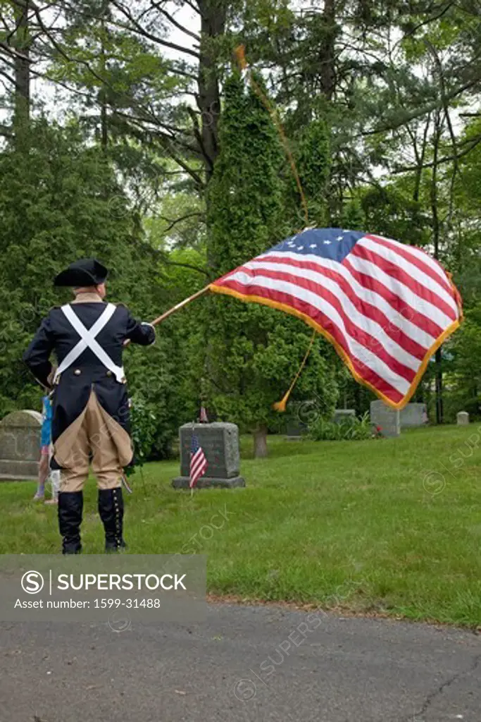 A Revolutionary Reenactor honors dead with an American Flag outside of Lexington, MA on Memorial Day, 2011