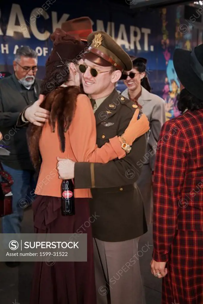 Man and woman in 1940's clothing hug during Pearl Harbor Day Troop train reenactment from Los Angeles Union Station to San Diego