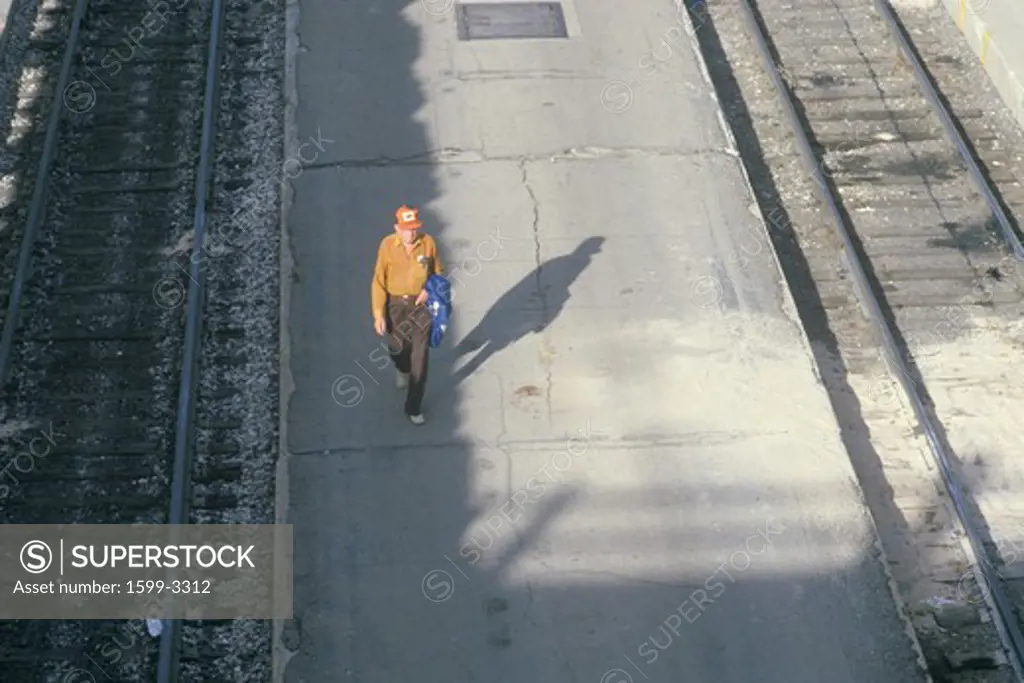 Lonely man walking along train tracks, Denver, Colorado