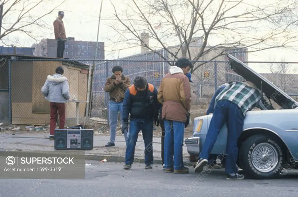 Men with boom box repairing car, South Bronx, New York