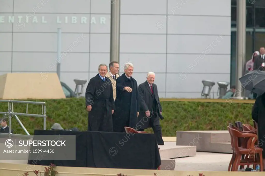 Former U.S. President Bill Clinton waves from the stage accompanied by President George W. Bush, former presidents Jimmy Carter and George H. W. Bush during the official opening ceremony of the Clinton Presidential Library November 18, 2004 in Little Rock, AK
