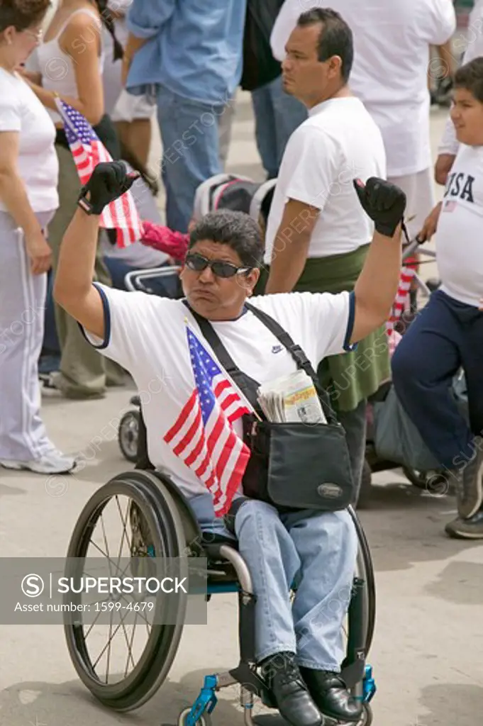 Man in wheel chair holds US flag in sympathy with hundreds of thousands of immigrants participating in march for Immigrants and Mexicans protesting against Illegal Immigration reform by U.S. Congress, Los Angeles, CA, May 1, 2006