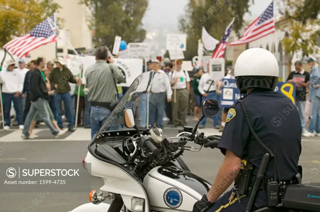 A motorcycle policeman looks at protesters against George W. Bush and the Iraq War at an anti-Iraq War protest march in Santa Barbara, California on March 17, 2007