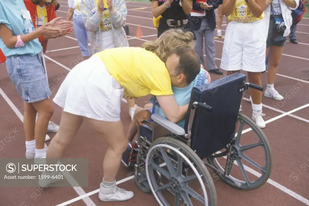 Special Olympics athlete in wheelchair, crossing finish line, being congratulated, UCLA, CA