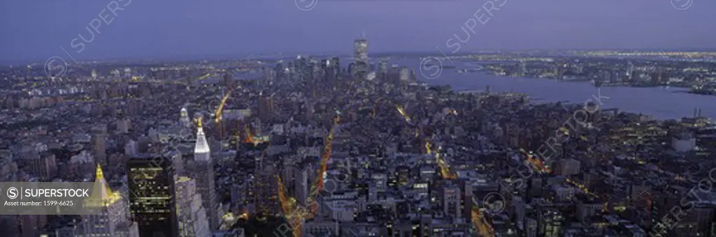 This is the north to south view of New York City from the Empire State Building. The lights of the skyscrapers are on as it dusk.