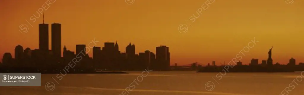 This is the Manhattan skyline from New Jersey. It shows the Statue of Liberty on the right, the world Trade Towers on the left and the skyline in silhouette at sunrise.