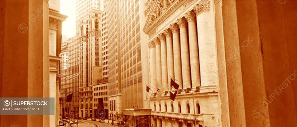 This is a sepiatone view looking at the exterior of the New York Stock Exchange on Wall Street. It is framed by two white columns.