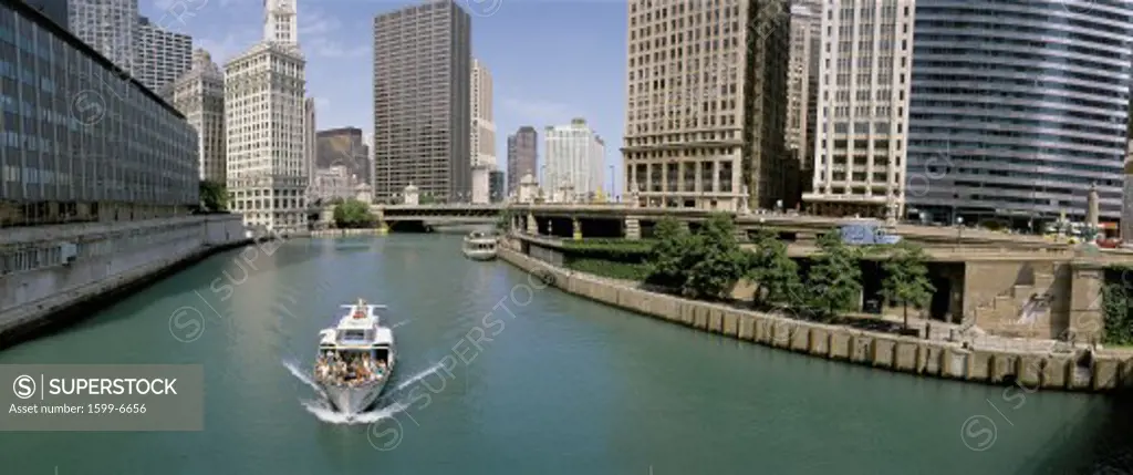 This is a tour boat on the Chicago River during summer. The Chicago Tribune Building, Chicago Sun Times Building, and the IBM Building surround the river.