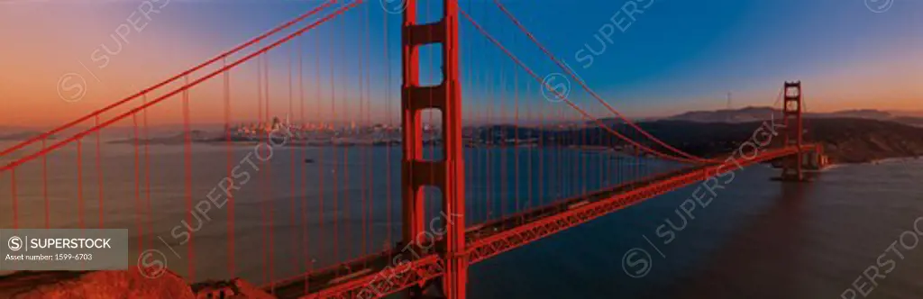 This is the Golden Gate Bridge at sunset. It is the view from the Marin Headlands. The skyline is small in the distance.
