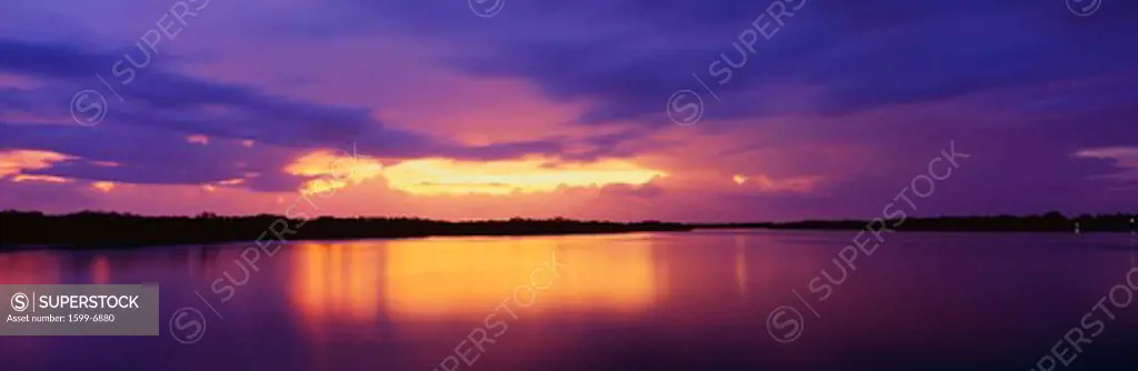 This is the ocean and Pine Island at sunset. There is a pinkish purple cast in the sky that is reflected in the water. The nearby land is in silhouette.