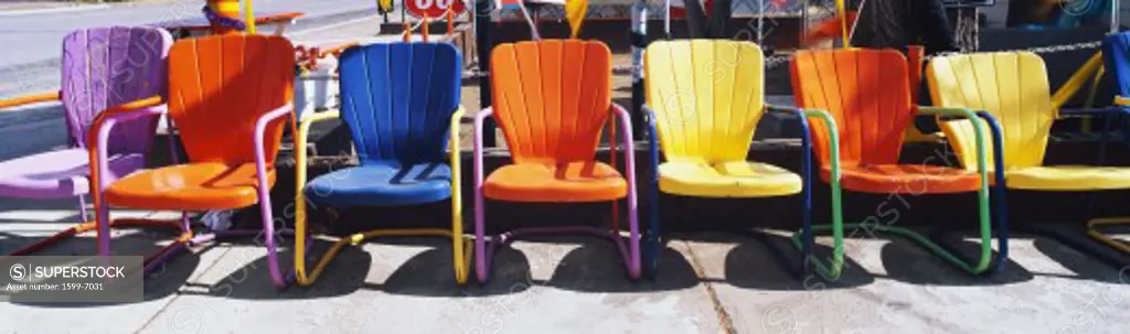 This is a close up of multi-colored metal lawn chairs. They are located outdoors on Route 66.