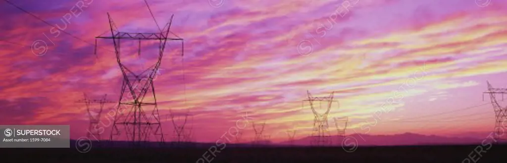 These are electricity pylons located near Hoover Dam. They are set against a pinkish orange sunset sky.