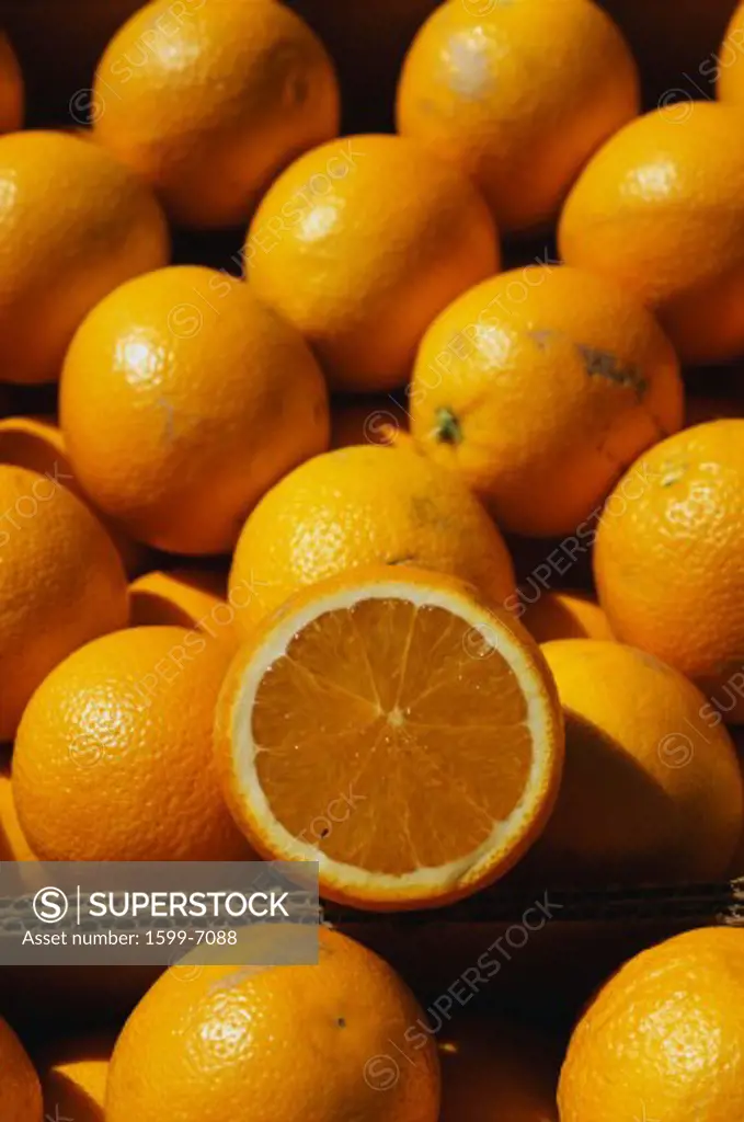 This is a close up of a boxes of oranges. One of the oranges has been sliced in half.