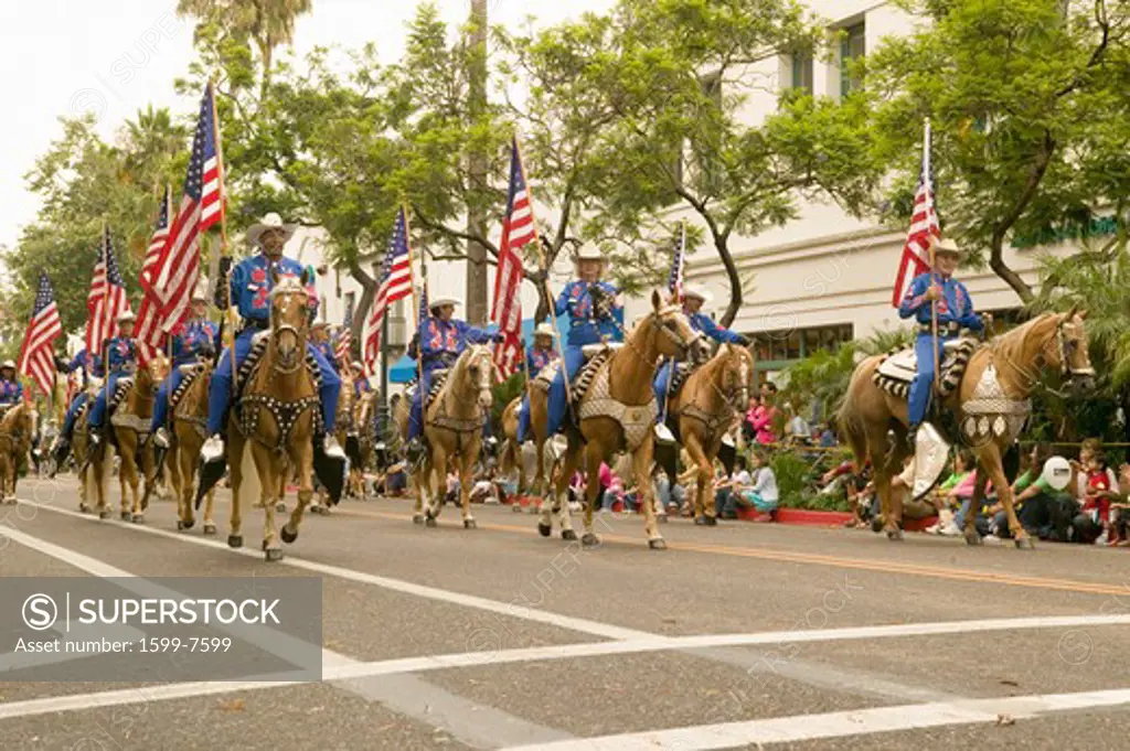 Cowboys on horseback with American Flags displayed during opening day parade down State Street, Santa Barbara, CA, Old Spanish Days Fiesta, August 2006