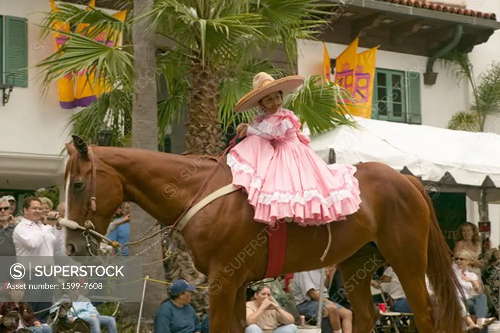 Young girl in pink dress rides horse in annual Old Spanish Days Fiesta held every August in Santa Barbara, California