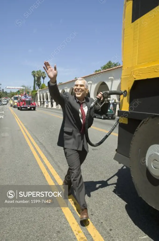 Actor impersonating George W. Bush pumping gas into a Hummer vehicle makes its way down main street during a Fourth of July parade in Ojai, CA