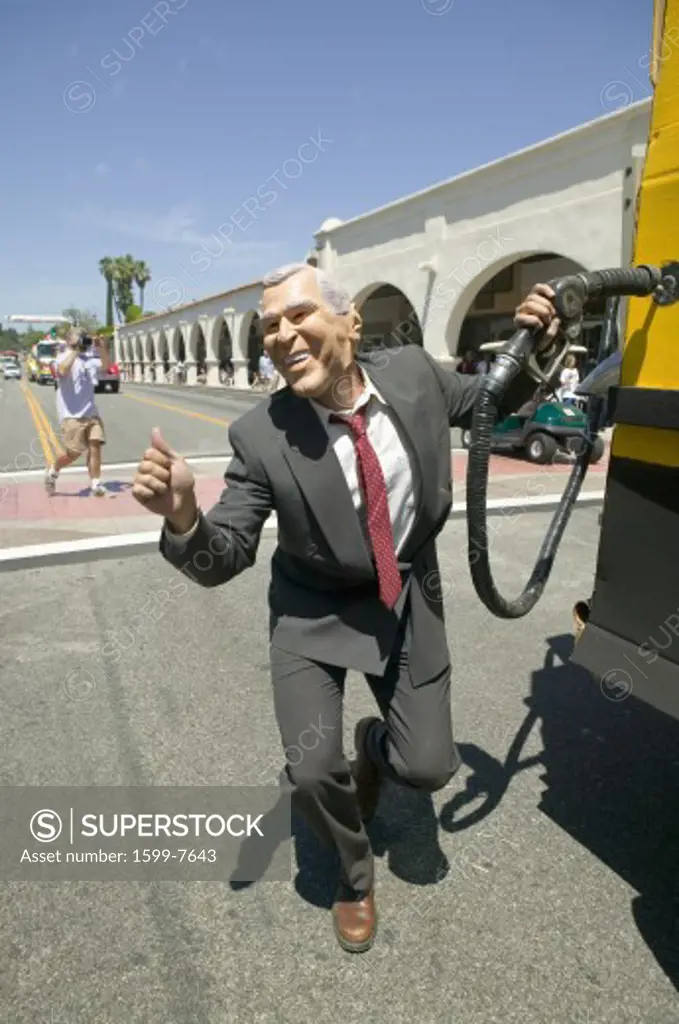 Actor impersonating George W. Bush pumping gas into a Hummer vehicle makes its way down main street during a Fourth of July parade in Ojai, CA
