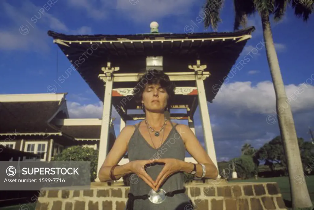 Woman meditates at shrine in Buddhist Cemetery in Maui Hawaii