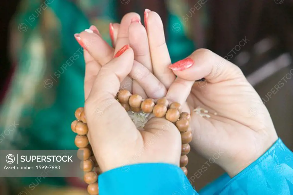 A woman's hands hold prayer beads and rice at an Amitabha Empowerment Buddhist Ceremony, Meditation Mount in Ojai, CA    