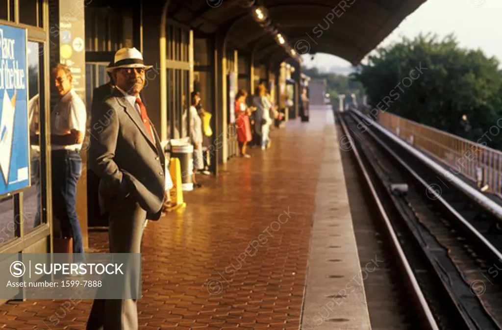A business man stands waiting for a Metro rail commuter train at sunrise, National Airport, Washington, D.C.