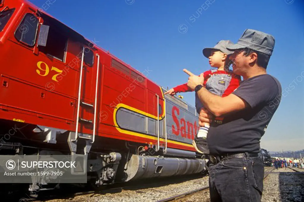 A father and son in engineer caps look at a historic Santa Fe diesel train in Los Angeles, CA