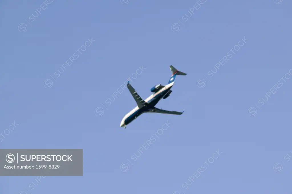 Commercial jet airplane flies overhead in a clear blue sky.