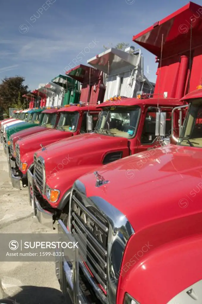 Bright red Mack dump trucks line the road in a row, in Maine near the New Hampshire border