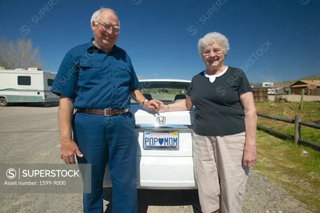 Elderly couple pose with California license plate that reads Pop loves Mom”